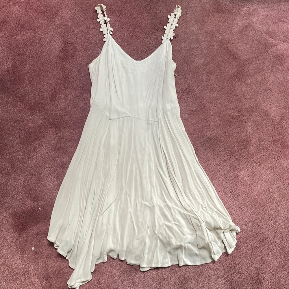 Cream asymmetrical sun dress with flower detail straps.